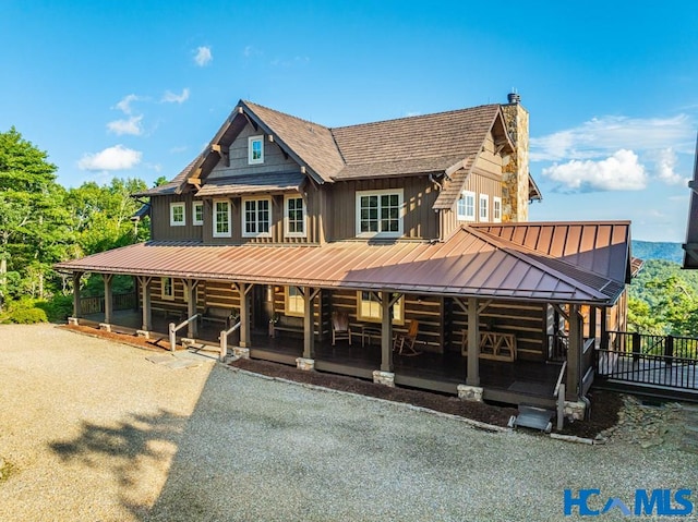 view of front facade featuring a standing seam roof, a chimney, metal roof, and board and batten siding