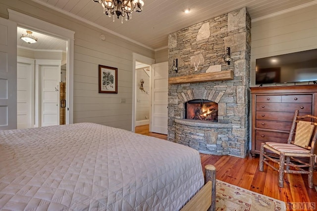 bedroom with wood-type flooring, wooden ceiling, ornamental molding, wooden walls, and a fireplace