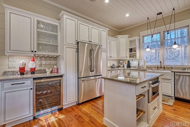 kitchen with wine cooler, stainless steel appliances, white cabinets, and ornamental molding