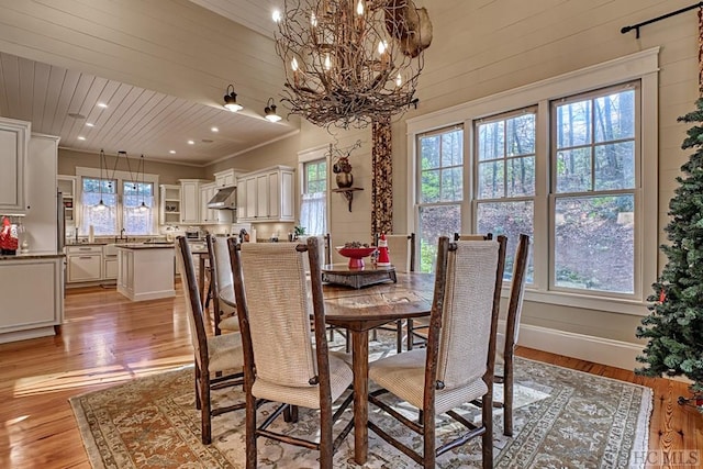 dining room featuring light wood-type flooring, crown molding, wooden ceiling, and a notable chandelier