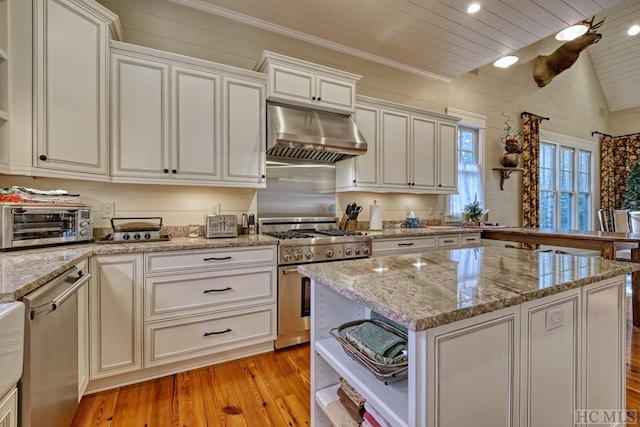 kitchen with range hood, stainless steel appliances, light stone counters, light hardwood / wood-style floors, and white cabinets