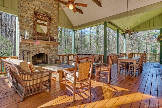 sunroom with ceiling fan, lofted ceiling with beams, and an outdoor stone fireplace