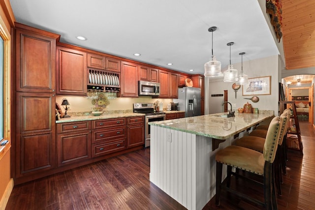 293 Gem Creek Rd, Cullowhee, NC 28723 - kitchen with appliances with stainless steel finishes, a breakfast bar area, a peninsula, dark wood-style floors, and light stone countertops