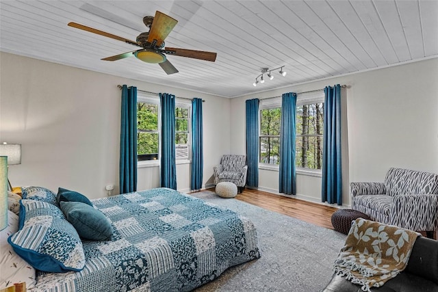 bedroom with rail lighting, hardwood / wood-style floors, multiple windows, and wooden ceiling