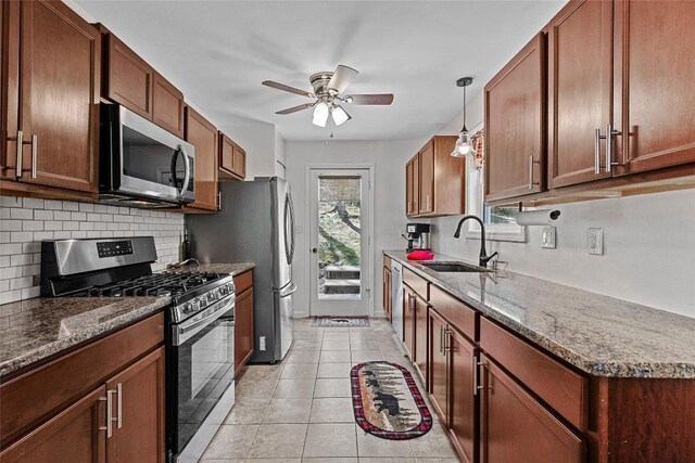 kitchen featuring sink, backsplash, stainless steel appliances, light tile patterned flooring, and decorative light fixtures