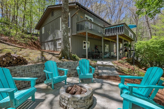 back of house featuring a wooden deck, a patio area, and a fire pit