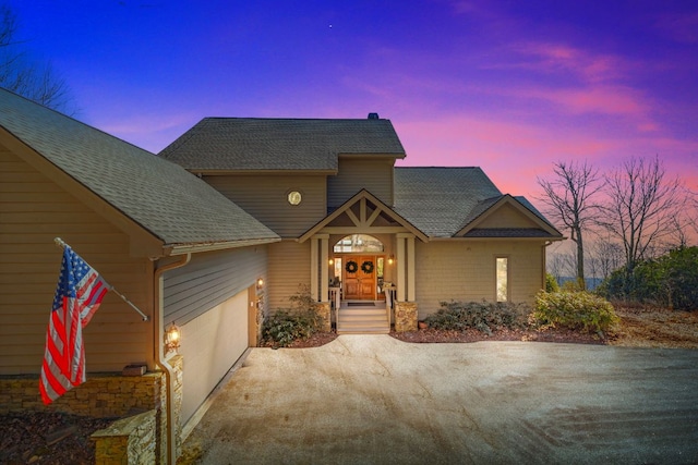 view of front of home featuring an attached garage, driveway, and a shingled roof