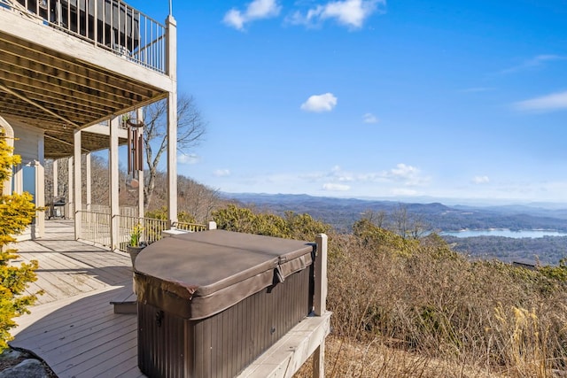 deck with a hot tub and a water and mountain view