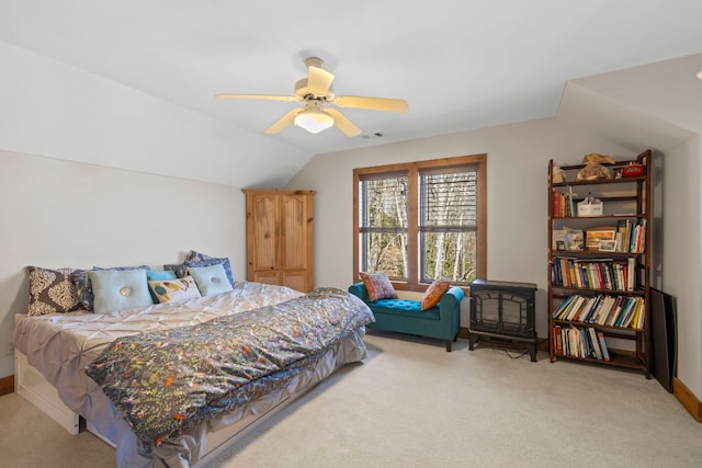 bedroom featuring lofted ceiling, a wood stove, a ceiling fan, and light colored carpet