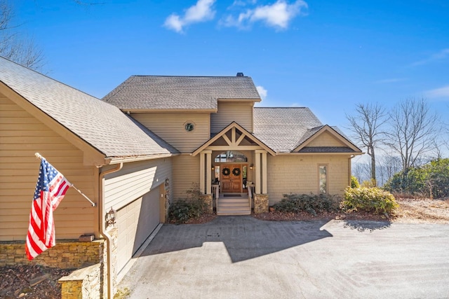 view of front of home with aphalt driveway, an attached garage, and a shingled roof