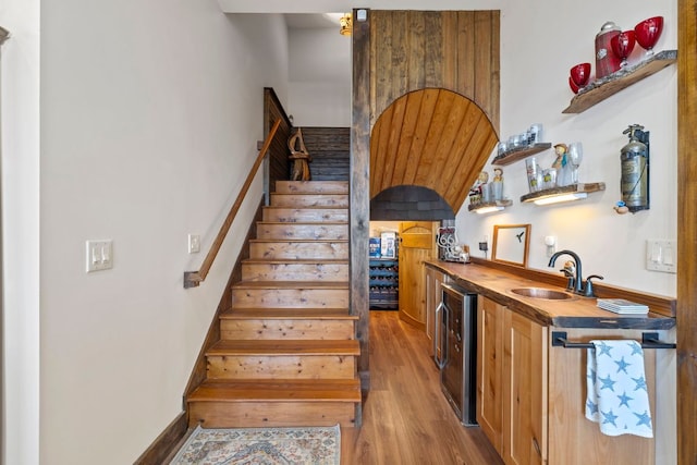 stairway with wine cooler, indoor wet bar, a barn door, wood finished floors, and baseboards