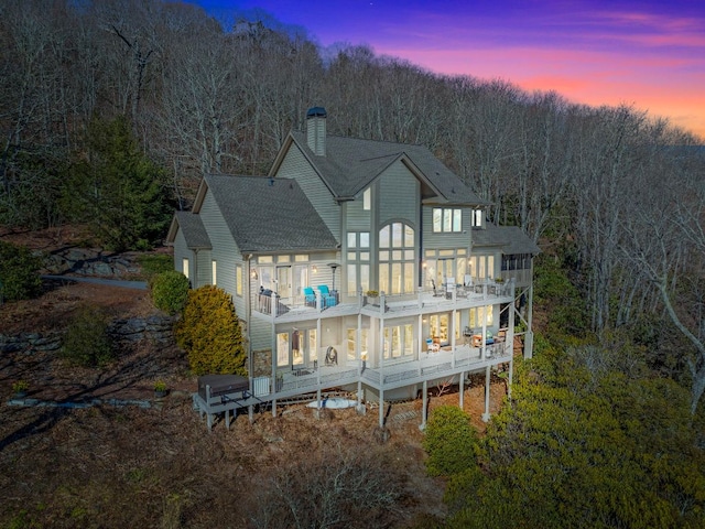 rear view of house with a shingled roof, a chimney, and a balcony