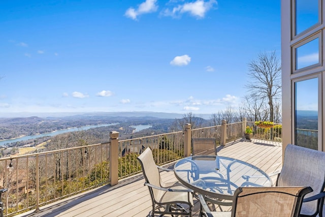 wooden terrace with outdoor dining space and a water and mountain view