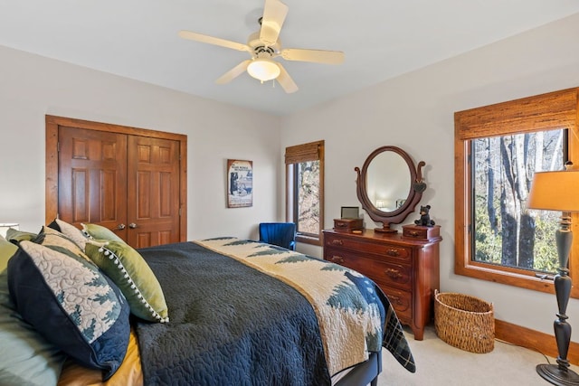 bedroom with baseboards, a closet, a ceiling fan, and carpet flooring