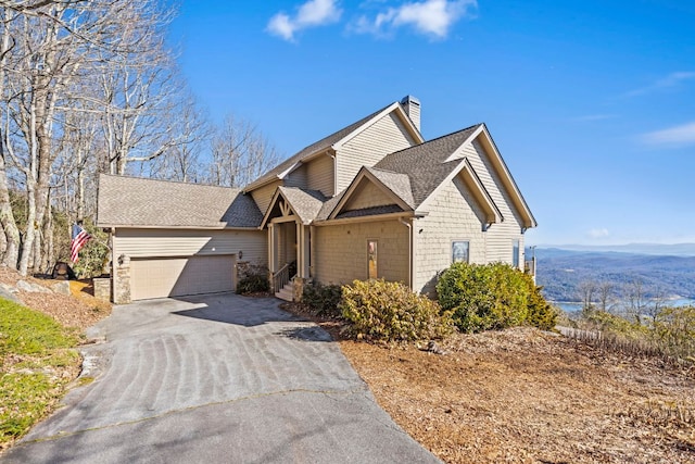 view of front of property with a garage, driveway, a chimney, and a shingled roof