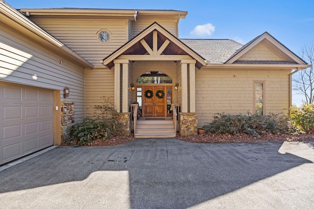 entrance to property featuring a garage and aphalt driveway