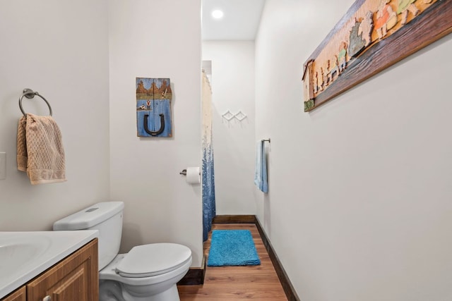 bathroom featuring toilet, baseboards, wood finished floors, and vanity