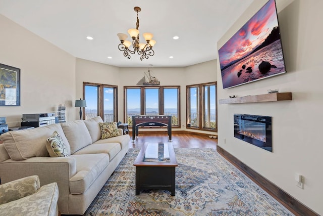 living room featuring dark wood-style flooring, plenty of natural light, a glass covered fireplace, and recessed lighting