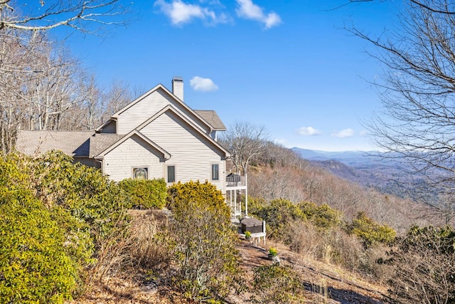 view of home's exterior featuring a balcony, a chimney, and a mountain view