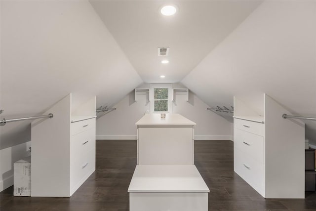 spacious closet featuring visible vents, vaulted ceiling, and dark wood-type flooring