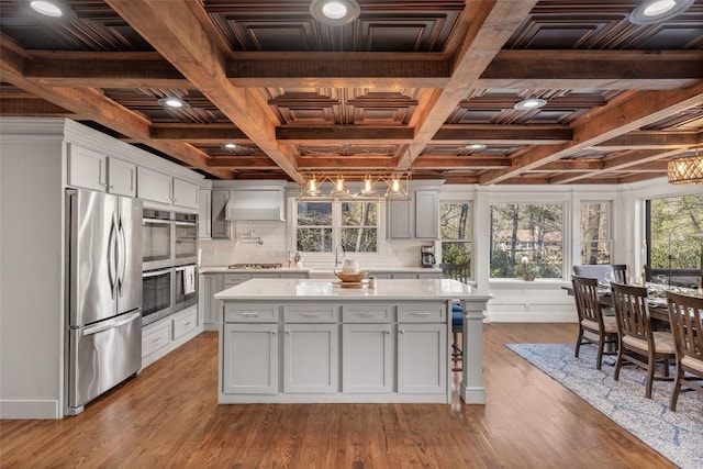 kitchen with stainless steel appliances, wood finished floors, light countertops, and custom range hood