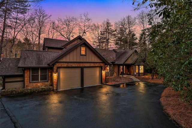 view of front of house featuring a garage, aphalt driveway, board and batten siding, and roof with shingles