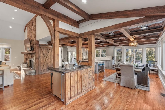 kitchen with a wealth of natural light, light wood-type flooring, freestanding refrigerator, and lofted ceiling with beams