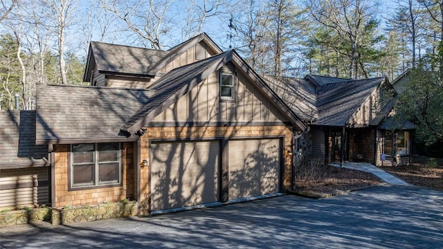 exterior space featuring a garage, aphalt driveway, and roof with shingles