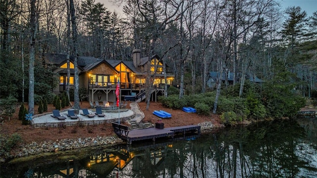 back of property with a chimney, an outdoor fire pit, a patio area, a wooden deck, and stairs