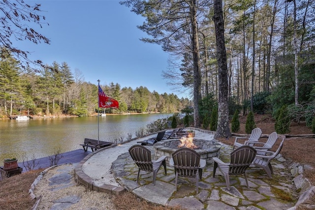 view of patio / terrace with an outdoor fire pit, a water view, a wooded view, and a dock