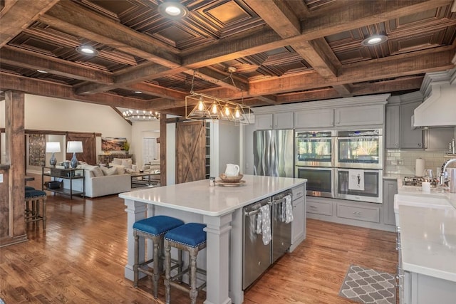 kitchen featuring light wood-style floors, a barn door, stainless steel appliances, and light countertops