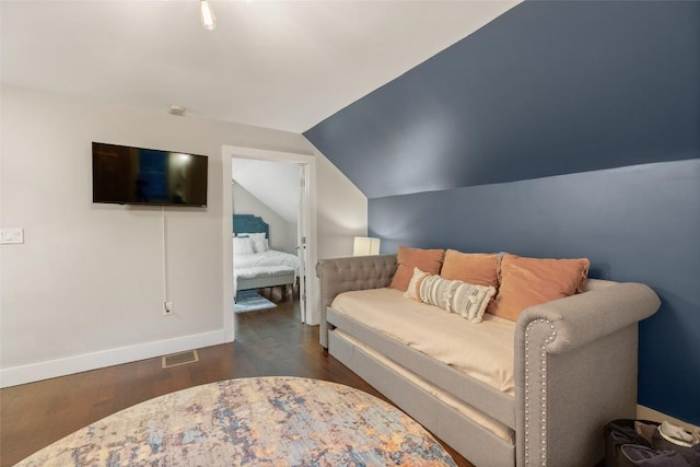 bedroom with lofted ceiling, wood finished floors, visible vents, and baseboards