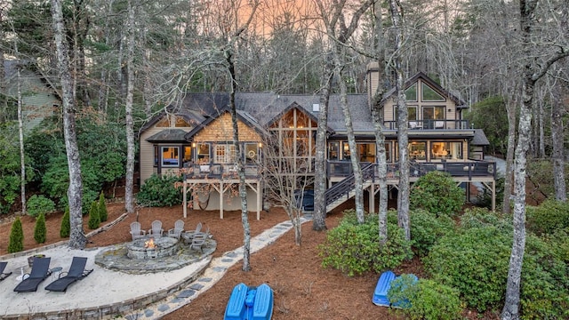 rear view of house with a fire pit, a chimney, stairway, roof with shingles, and a wooden deck