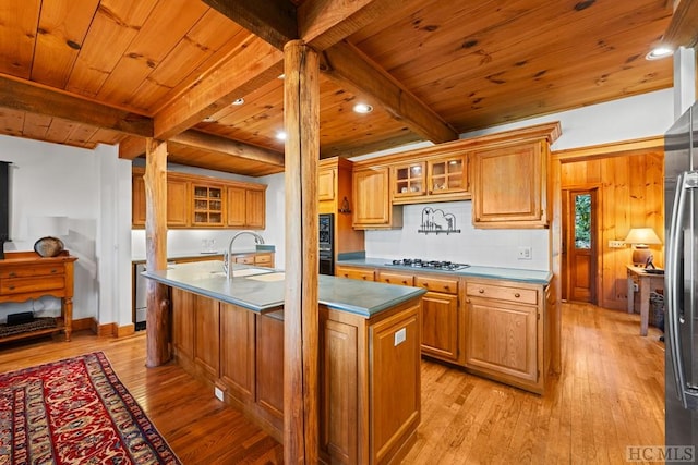 kitchen with sink, an island with sink, stainless steel gas cooktop, wooden ceiling, and beamed ceiling