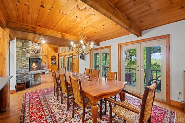 dining space with light hardwood / wood-style flooring, a fireplace, beam ceiling, and french doors