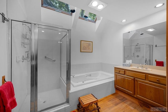 bathroom featuring vanity, plus walk in shower, a skylight, and hardwood / wood-style floors