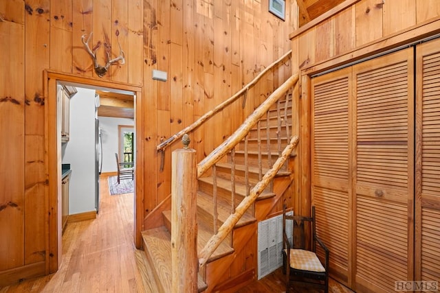 stairs with hardwood / wood-style flooring and wood walls