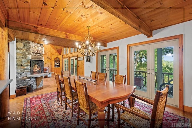 dining room featuring french doors, a stone fireplace, wood ceiling, light wood-type flooring, and beamed ceiling