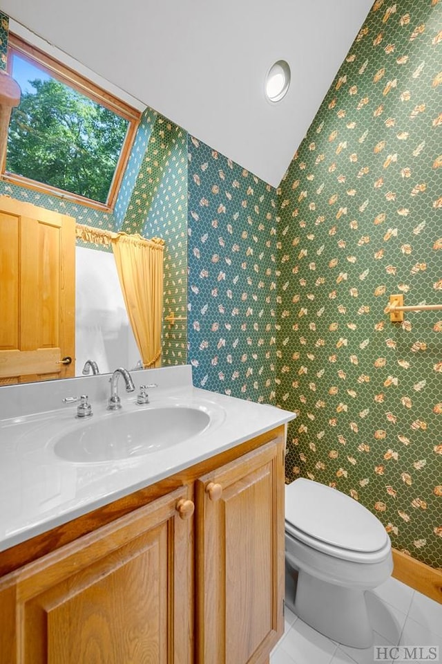 bathroom featuring tile patterned flooring, vanity, lofted ceiling, and toilet