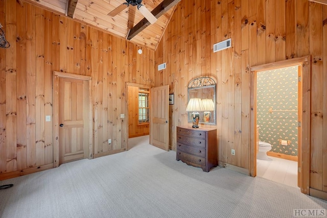 unfurnished bedroom featuring beamed ceiling, ensuite bath, high vaulted ceiling, and light carpet