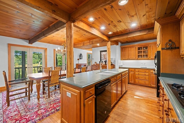 kitchen featuring beamed ceiling, sink, black appliances, a center island with sink, and light hardwood / wood-style flooring