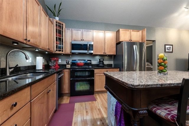 60 Pine Cone Ct, Sapphire, NC 28774 - kitchen with appliances with stainless steel finishes, a sink, light wood-style flooring, dark stone counters, and brown cabinets