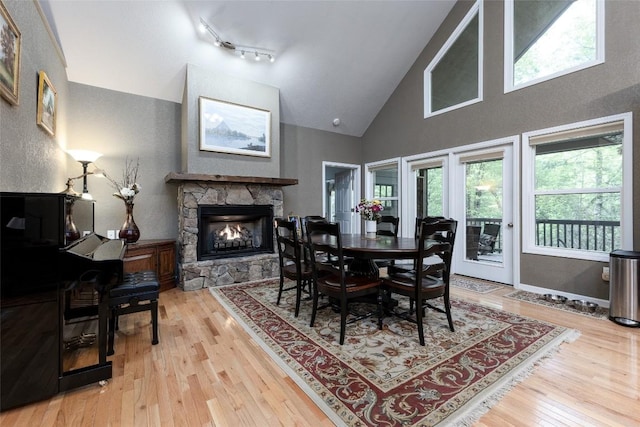 60 Pine Cone Ct, Sapphire, NC 28774 - dining space featuring a stone fireplace, light wood-type flooring, healthy amount of natural light, and high vaulted ceiling
