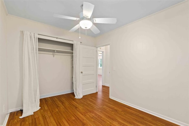 unfurnished bedroom featuring wood finished floors, baseboards, a closet, and a ceiling fan