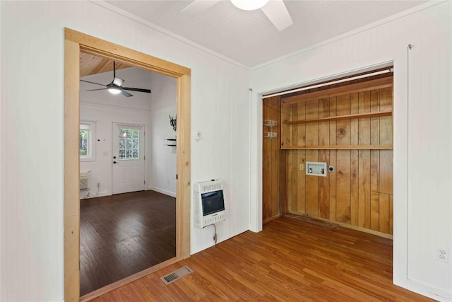 spare room with ceiling fan, heating unit, ornamental molding, and wood finished floors