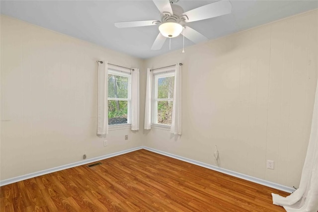 unfurnished room with wood finished floors, baseboards, and a ceiling fan