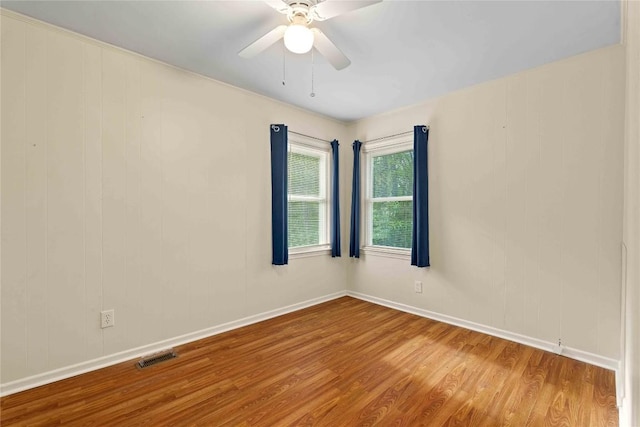 empty room featuring wood finished floors, baseboards, and a ceiling fan