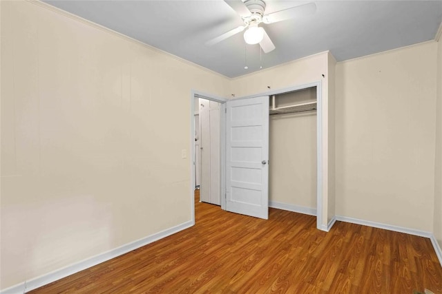 unfurnished bedroom featuring wood finished floors, baseboards, a ceiling fan, and a closet
