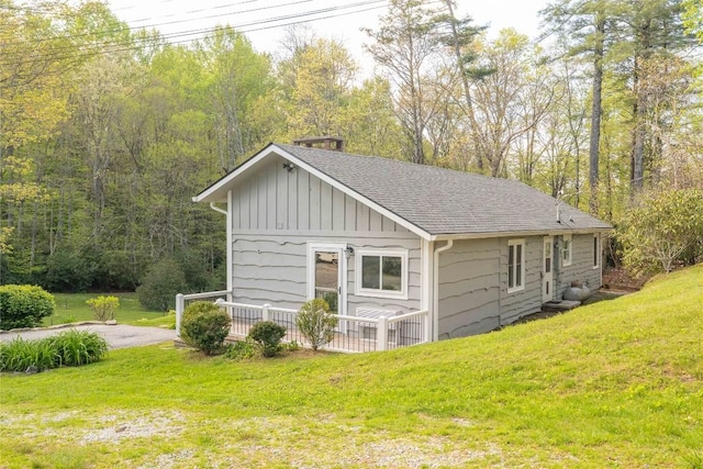 view of property exterior with board and batten siding, a yard, a shingled roof, and a wooden deck