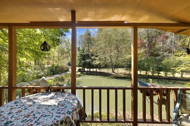 sunroom with a water view, a healthy amount of sunlight, and wooden ceiling